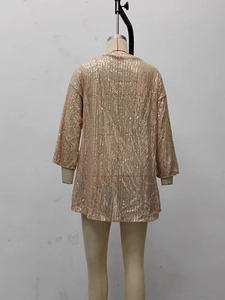 Close-up of shimmering champagne gold sequins on a loose-fit long sleeve cardigan