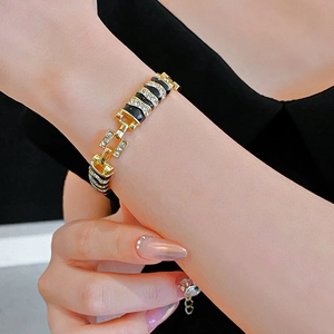 Close-up of gold link bracelet with black enamel and sparkling rhinestones on woman's wrist