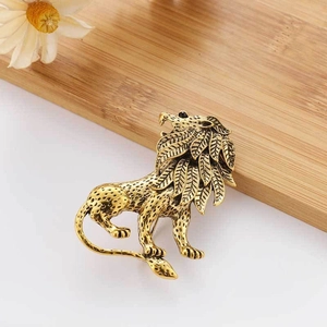 Vintage gold lion brooch with detailed mane on natural wood background with white flowers