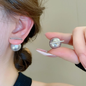 Macro detail of gray pearl earrings with sparkling zircon bar design on model