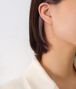 Detail of elegant gold long chain drop earrings with spherical pendants on model