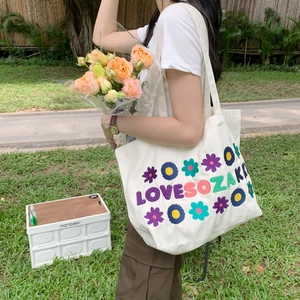 Detailed embroidery floral pattern and LOVESOZAKI text on a white canvas tote bag