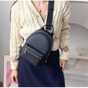 Close-up of black lychee grain leather crossbody bag with silver zippers and strap detail
