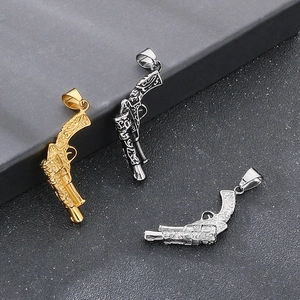 Detailed view of gun-shaped steel pendants in gold, black, and silver with carvings