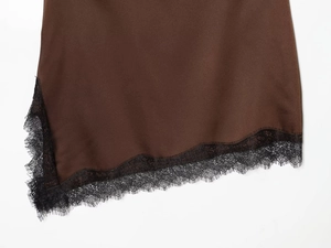 Dettaglio dell'orlo della gonna in raso marrone scuro con bordo in pizzo nero