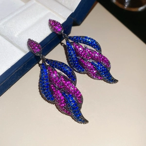 Macro view of leaf-shaped drop earrings with purple and blue crystals on dark metal