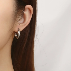 Close-up of silver heart-shaped hoop earrings worn by a model for a chic retro look