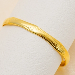 Bracelet jonc bambou en acier inoxydable doré 18K sur un support de cylindre blanc