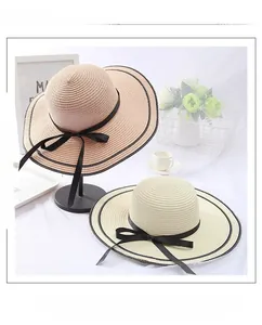 Detailed straw hat weaving with elegant black ribbon bow in pink and beige colors