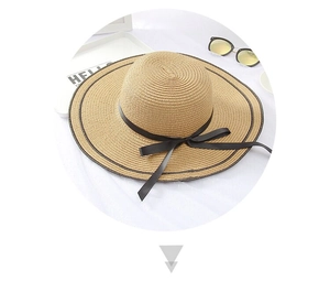 Detail of a straw sun hat with wide brim, black ribbon bow, and woven texture for summer