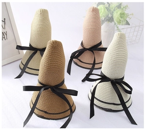 Close-up of wide brim straw hats in four colors with black ribbon bows for beach vacation