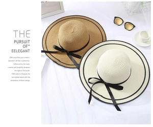 Detail of straw sun hats with black ribbon bows and contrast trim for summer beach travel