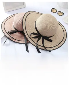 Close-up of foldable straw hats with wide wavy brims and black ribbon bow decorations
