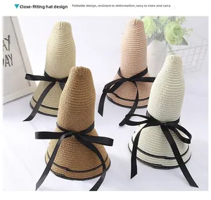 Detail view of foldable straw sun hats with black ribbon bows in multiple colors