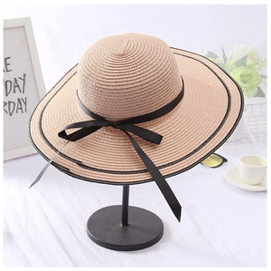Detail of pink straw hat with black edge ribbon and bow on a metal display stand