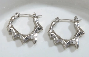 Macro detail of silver irregular lava earrings with modern geometric liquid texture
