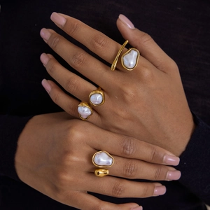 Detailed view of three baroque pearl rings with gold plating on a hand model