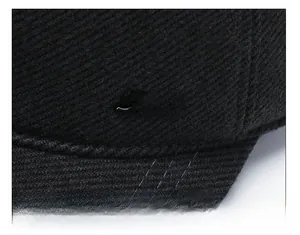 Gros plan du tissu en sergé noir avec logo métallique 'Sport' sur une casquette d'hiver épaisse