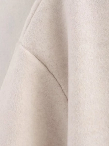 Gros plan des coutures d'épaule et de la texture laineuse du blouson aviateur beige