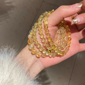 Macro shot of multi-layer citrine bead bracelet with golden flower accents and crystal texture