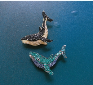 Detailed view of whale brooches featuring sparkling crystals and polished metal finish