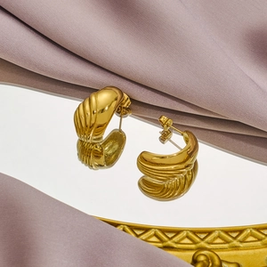 Golden textured wave earrings with retro shell design on silk and mirror background
