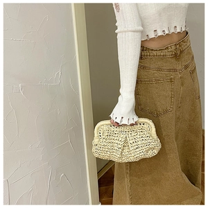 Detail shot showing the natural straw texture and hand-held style of this woven clutch bag
