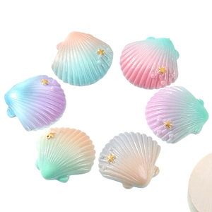 Resin seashell DIY charms with gradient colors, pearls and gold stars on white background