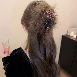 Detailed view of a brown feather hair claw clip with beads styled on a model long hair