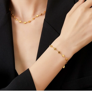 Close-up of 18K gold plated bead chain necklace and matching bracelet set on a model