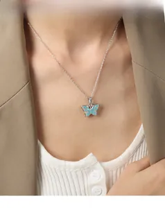 Détail d'un pendentif papillon argenté avec émail bleu ciel sur une fine chaîne élégante