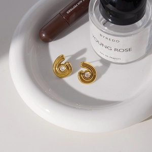 Boucles d'oreilles spirales dorées de luxe avec zircons sur un plateau en céramique