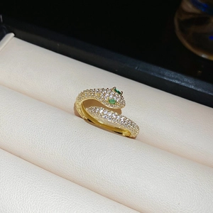 Detailed close-up of gold snake ring with white cubic zirconia and green gemstone eyes