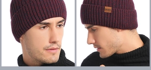 Detail of burgundy thick knit winter hat with brown leather brand tag for cold weather