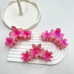 Dettaglio di tre mollette per capelli a forma di plumeria rosa su vassoio decorativo