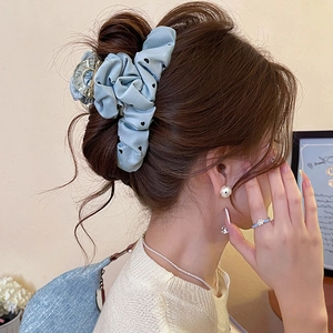 Blue fabric hair scrunchie claw clip with black heart patterns worn on hair