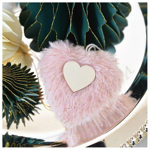 Close-up of pink faux fur heart ornament with a wooden center piece on a silver tray