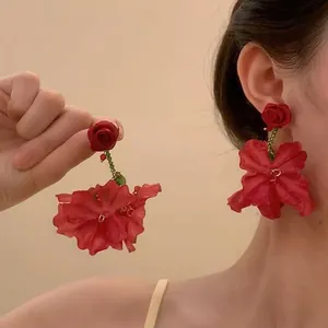 Gros plan de grandes boucles d'oreilles fleurs rouges avec pétales en satin