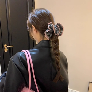 Close-up of black and white checkered hair scrunchie with pink edges worn on a braid