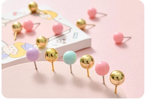 Macro shot of colorful round thumb tacks in pink, gold, and mint green for office decor