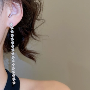 Close-up of model wearing silver tassel earrings with square rhinestones