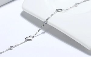 Macro shot of S925 sterling silver heart bracelet with round zircon on white ceramic