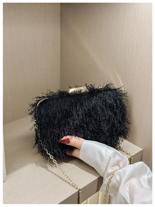 Detail of evening clutch bag featuring black fringe texture and gold metal chain strap