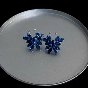 Macro shot of blue crystal butterfly earrings on a silver plate with black background