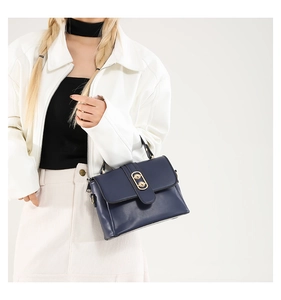 Detail of navy blue crossbody bag with gold double-ring lock and smooth leather texture
