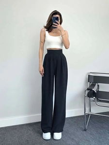 Détail du pantalon noir taille haute à jambes larges, offrant un tombé fluide et chic