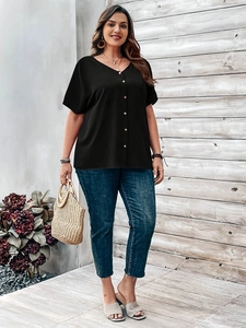 Detail of a casual black V-neck button-down shirt paired with cropped blue denim jeans
