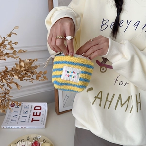 Detail of mini striped fleece makeup bag with zipper and logo label held by a hand