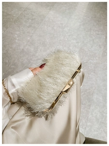 Detailed view of luxury evening clutch with white ostrich feathers and gold metal frame