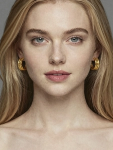 Detail view of triple-layered C-shape gold earrings with woven texture on model